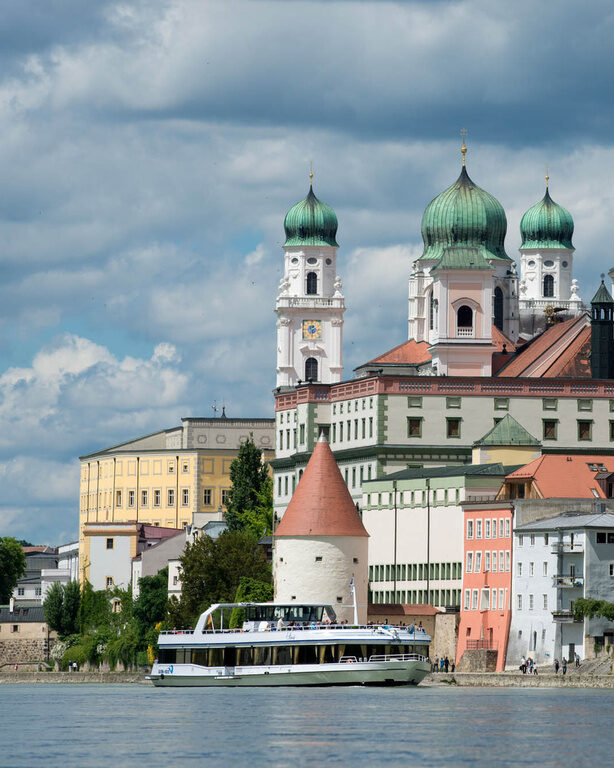 Blick auf den imposanten Dom von Passau, malerisch eingerahmt vom Fluss Inn im Vordergrund.
