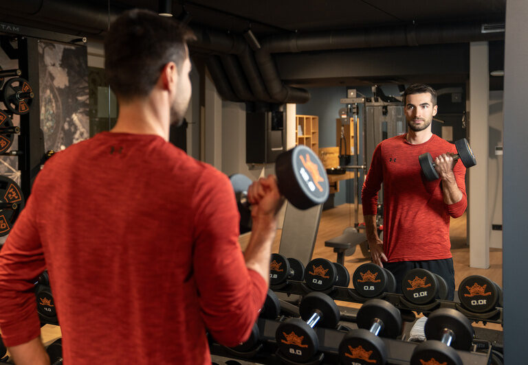 Mann trainiert mit Hanteln im hauseigenen Fitnessbereich des Hotels Dreiflüssehof in Passau